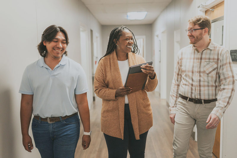 three people walking down hallway